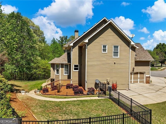 view of side of home featuring concrete driveway, fence, a chimney, and a yard