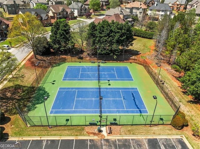 view of tennis court with fence and a residential view
