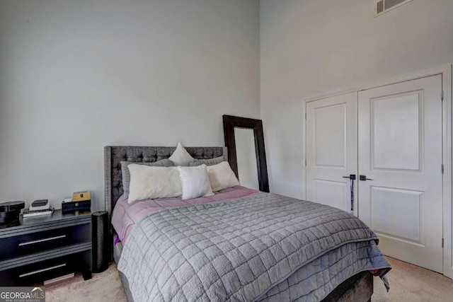 bedroom with visible vents, a towering ceiling, and light carpet