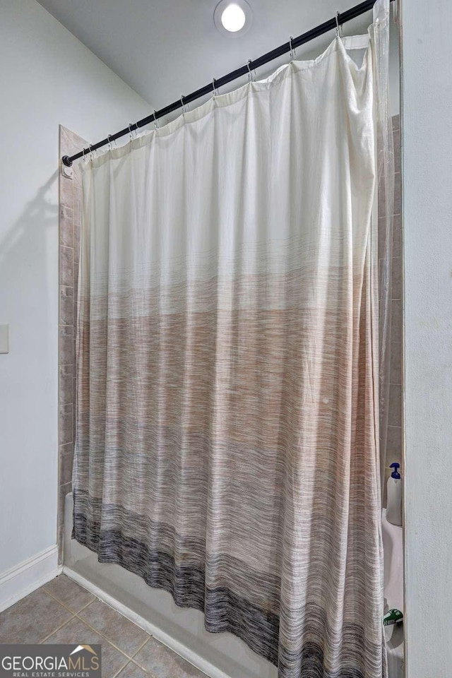 full bath featuring shower / tub combo with curtain, tile patterned floors, and baseboards