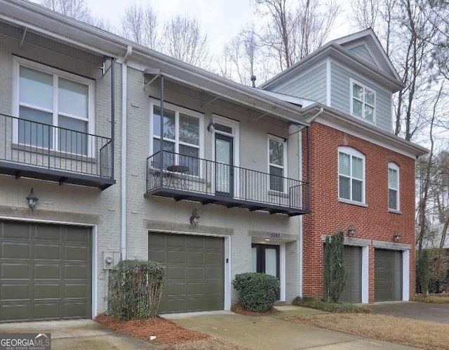 view of property with a balcony, brick siding, and a garage