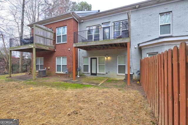 back of house featuring fence, a balcony, and brick siding