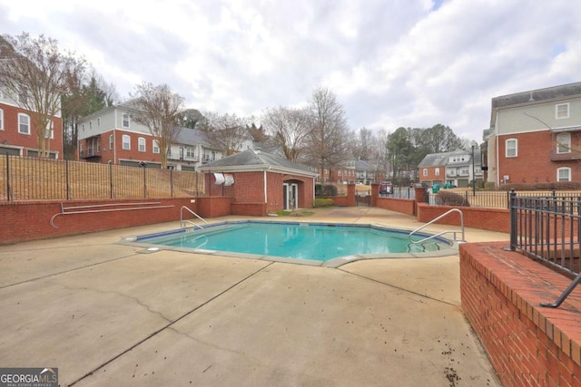 pool with a residential view, a patio area, and fence
