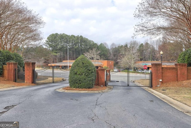 view of street with a gate, a gated entry, and curbs