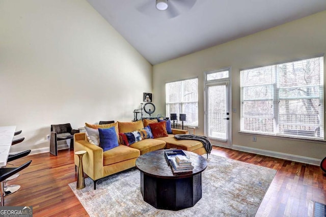 living room with baseboards, a ceiling fan, wood finished floors, and high vaulted ceiling