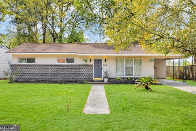 ranch-style home featuring fence, an attached carport, a front yard, and concrete driveway