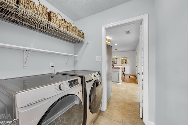 clothes washing area with washing machine and dryer, visible vents, an inviting chandelier, laundry area, and light tile patterned floors