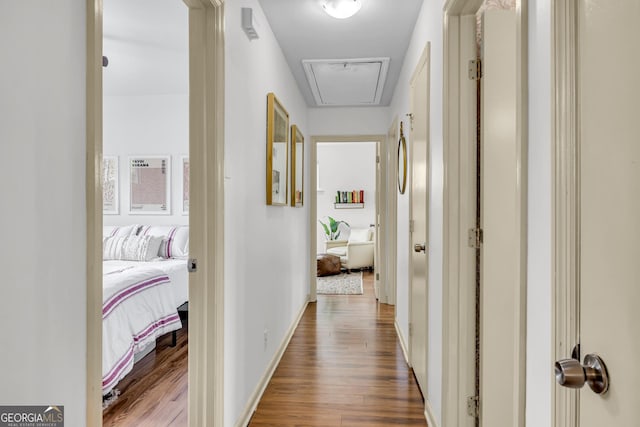 hallway featuring attic access and wood finished floors