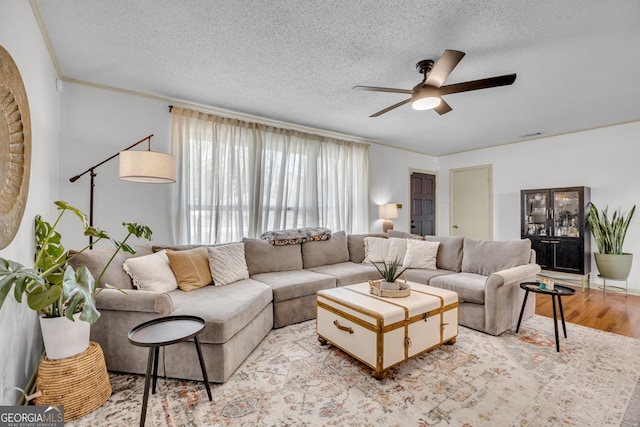 living area featuring a ceiling fan, visible vents, a textured ceiling, and light wood-style flooring
