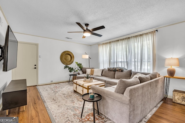 living room with wood finished floors, a textured ceiling, ceiling fan, and visible vents