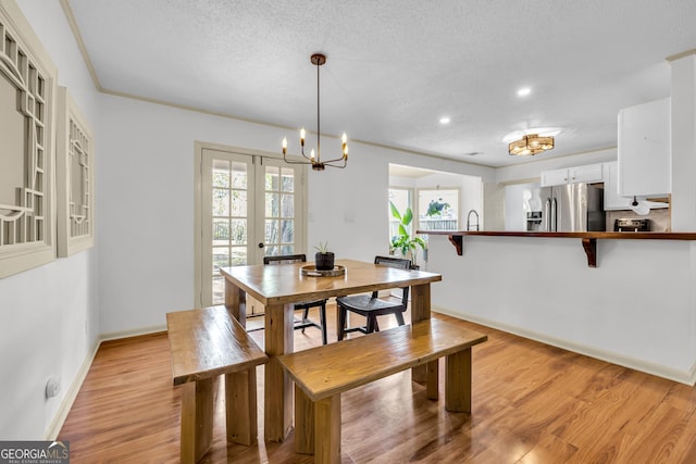 dining area featuring light wood-style flooring, a healthy amount of sunlight, baseboards, and a notable chandelier