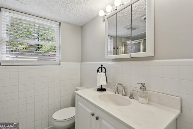 1649 Clairmont Way NE, Brookhaven, GA 30329 - bathroom with a wainscoted wall, a textured ceiling, toilet, tile walls, and vanity