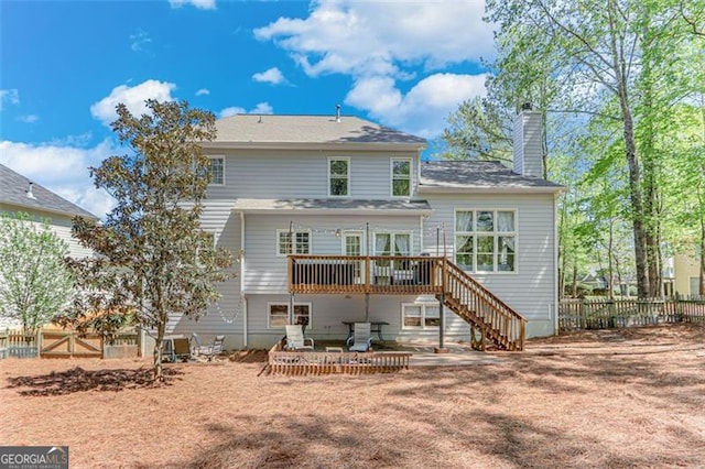 back of property with a chimney, stairs, fence, and a deck