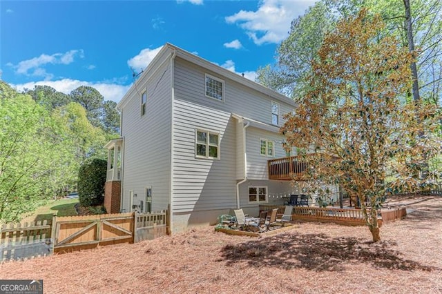 back of house featuring a gate, fence, and a deck