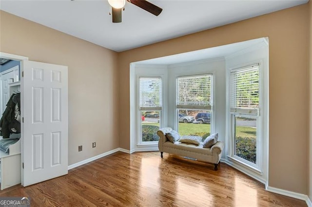 sitting room featuring baseboards, a ceiling fan, and wood finished floors