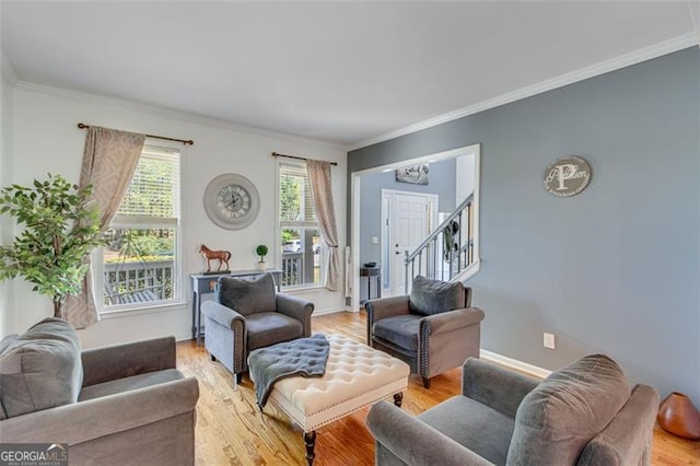 living area with light wood-type flooring, crown molding, baseboards, and a notable chandelier