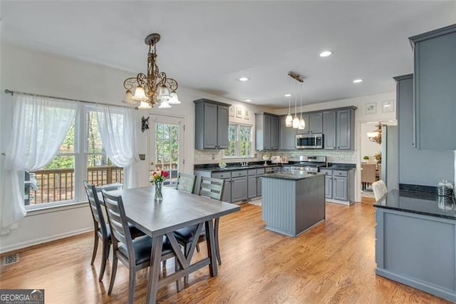 kitchen featuring stainless steel appliances, a center island, dark countertops, a notable chandelier, and gray cabinets