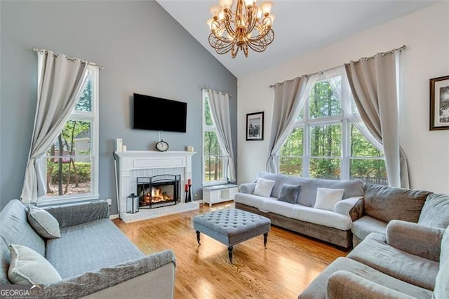 living room with a fireplace, wood finished floors, high vaulted ceiling, and a chandelier