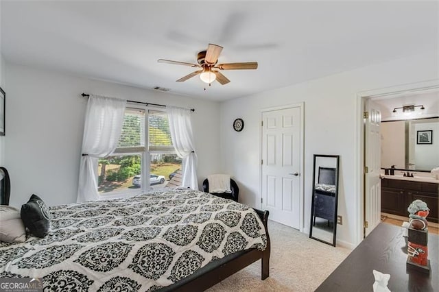 bedroom featuring connected bathroom, a ceiling fan, light carpet, and a sink