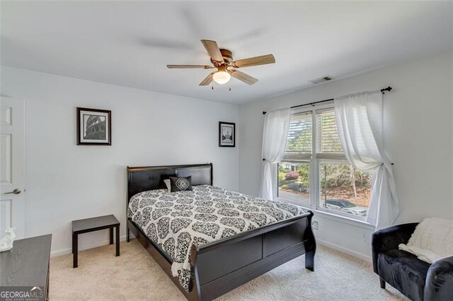 bedroom with ceiling fan, visible vents, baseboards, and light carpet