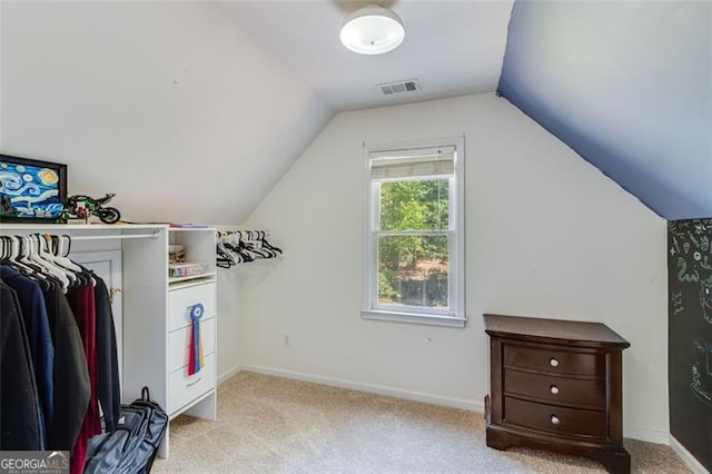 walk in closet with lofted ceiling, visible vents, and light colored carpet