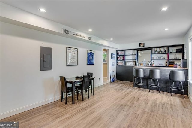 bar with indoor bar, wood finished floors, electric panel, and recessed lighting