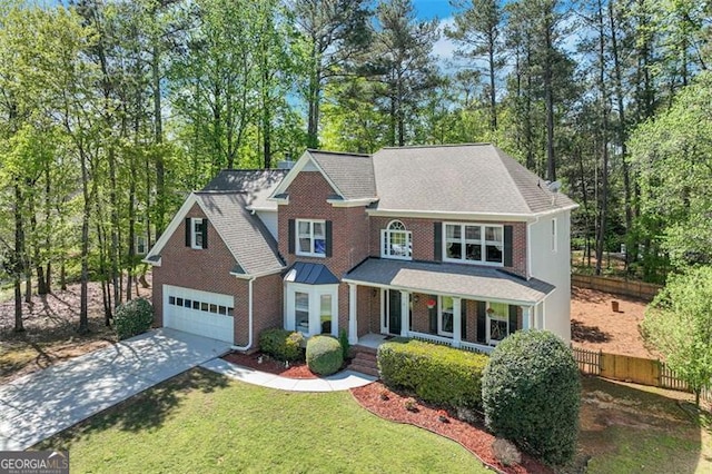 traditional home with fence, an attached garage, driveway, covered porch, and brick siding