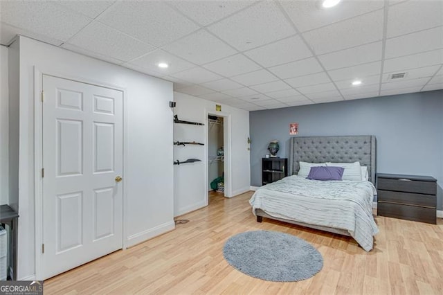 bedroom with a paneled ceiling and wood finished floors