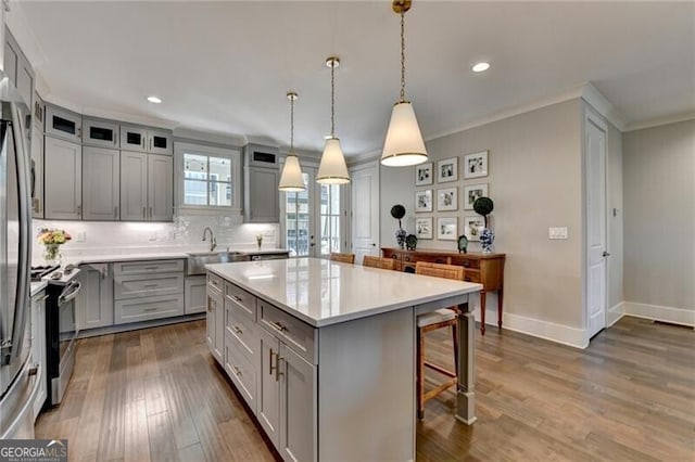 kitchen featuring a kitchen breakfast bar, crown molding, gray cabinetry, range, and dark wood-style flooring