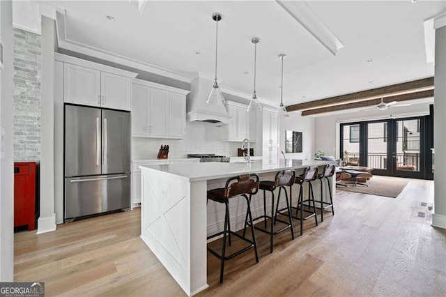 1268 Appleden Way Unit 17, Brookhaven, GA 30319 - kitchen with freestanding refrigerator, custom range hood, light wood finished floors, white cabinetry, and backsplash