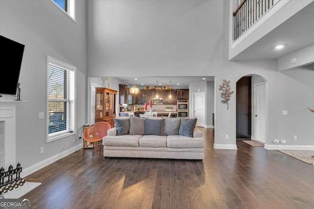 3206 Letha Woods Dr, Conyers, GA 30094 - living room featuring a towering ceiling, arched walkways, dark wood-style floors, and a fireplace with flush hearth