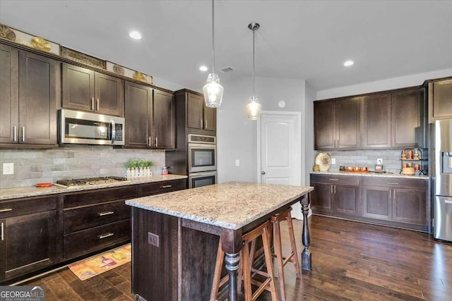 3206 Letha Woods Dr, Conyers, GA 30094 - kitchen featuring stainless steel appliances, backsplash, dark brown cabinets, light stone countertops, and decorative light fixtures