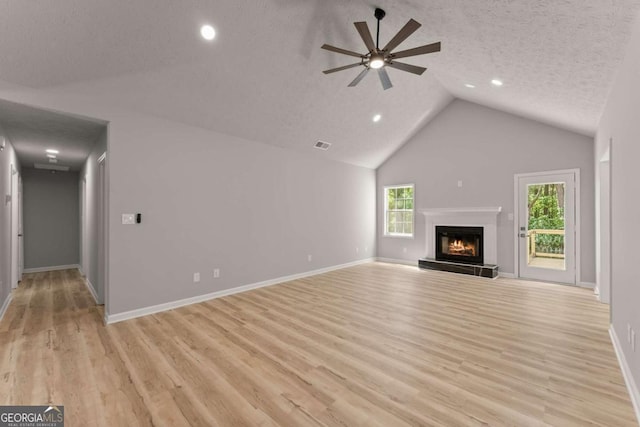 unfurnished living room with light wood-type flooring, baseboards, a glass covered fireplace, visible vents, and ceiling fan