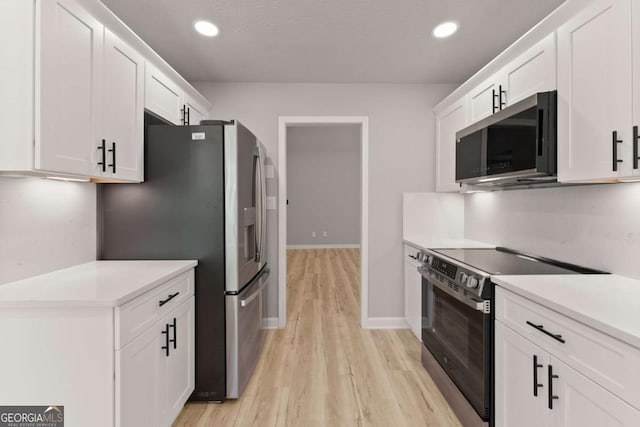 kitchen with white cabinets, stainless steel appliances, light wood-style flooring, baseboards, and light countertops