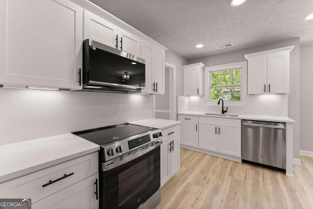 kitchen featuring a sink, stainless steel appliances, light countertops, white cabinetry, and visible vents