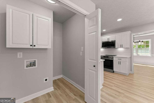 laundry room featuring light wood finished floors, a textured ceiling, baseboards, hookup for a washing machine, and laundry area