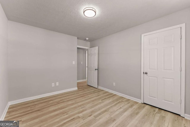 unfurnished bedroom with baseboards, light wood-style floors, and a textured ceiling