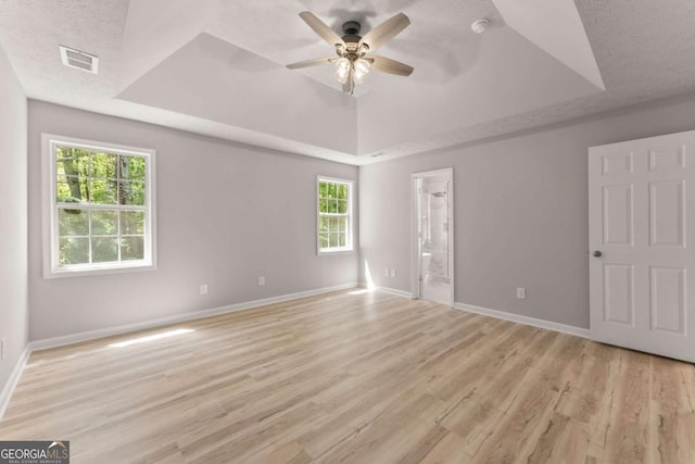 unfurnished bedroom featuring visible vents, baseboards, a tray ceiling, and light wood-type flooring