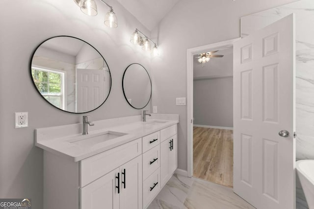 full bathroom with marble finish floor, a freestanding bath, a sink, and double vanity