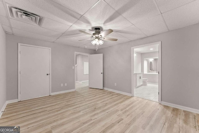 unfurnished bedroom with visible vents, light wood finished floors, a drop ceiling, and connected bathroom