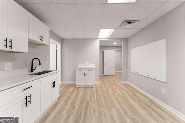 kitchen featuring a sink, light wood-type flooring, light countertops, white cabinetry, and visible vents