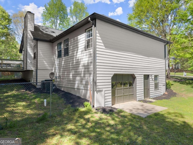 view of property exterior with fence, a chimney, a yard, and a garage
