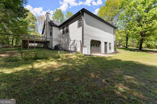view of home's exterior featuring an attached garage, a lawn, and a chimney