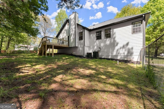 rear view of house with stairway, a chimney, fence, a yard, and a wooden deck