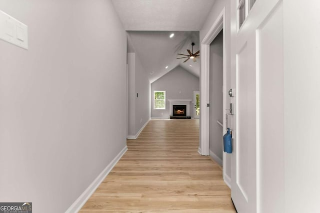 hall with recessed lighting, vaulted ceiling, light wood finished floors, and baseboards