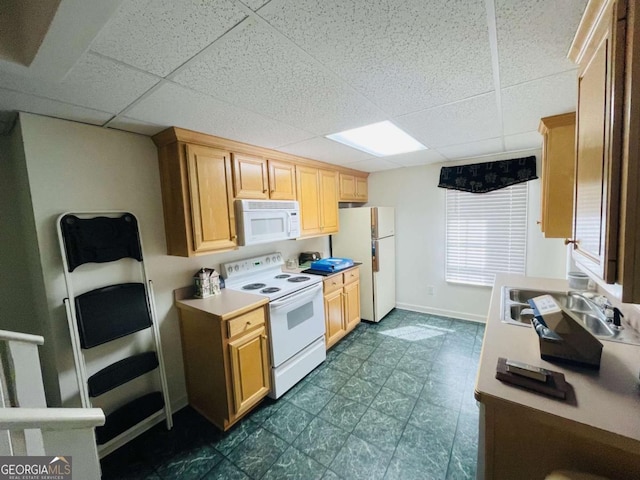 kitchen featuring baseboards, light countertops, white appliances, and a paneled ceiling