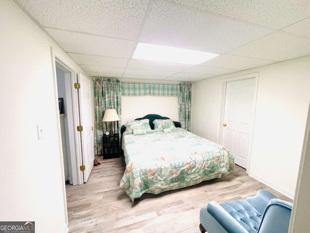 bedroom featuring baseboards, wood finished floors, and a drop ceiling