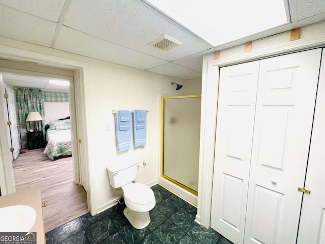 full bathroom featuring visible vents, a drop ceiling, a shower stall, and toilet