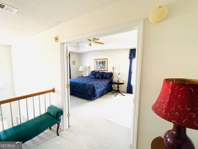 carpeted bedroom with a ceiling fan, a textured ceiling, and visible vents