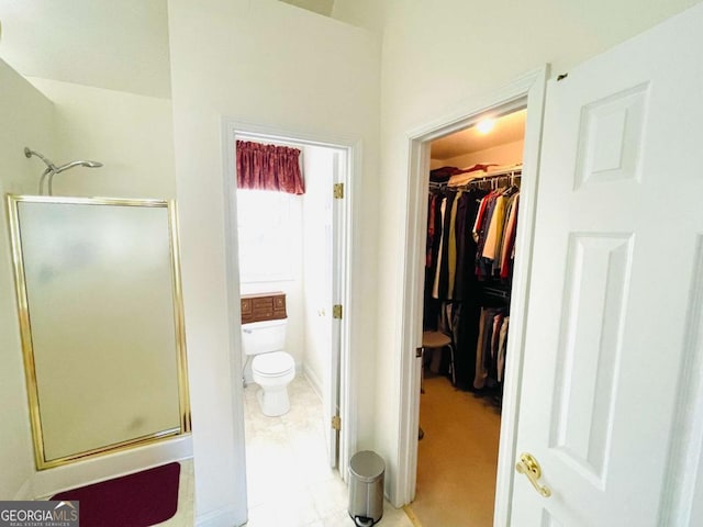 full bathroom with toilet, baseboards, tile patterned flooring, a shower stall, and a walk in closet